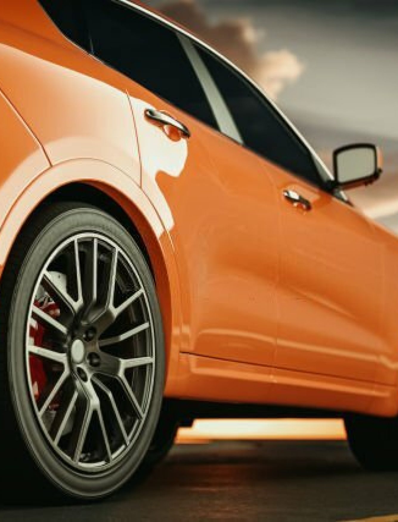 Close-up side view of an orange luxury sports car